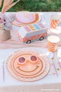 a table topped with plates and glasses next to a vase filled with flowers on top of a white table cloth