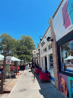 people are walking down the sidewalk in front of shops