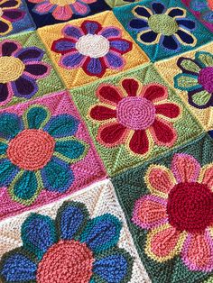 a crocheted blanket with colorful flowers on it's sides and one flower in the middle