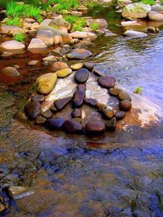 rocks arranged in the shape of a heart on top of a rock by a stream