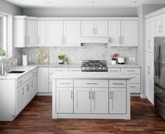 a kitchen with white cabinets and wood floors