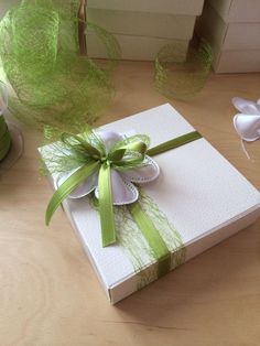 a white box with a green ribbon and bow on it sitting on a wooden table