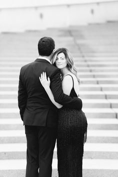 a man and woman embracing each other in front of stairs