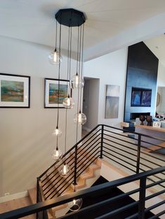 a staircase with lights hanging from it and pictures on the wall in front of it