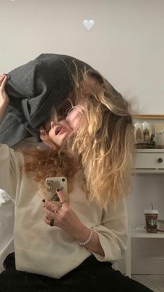 a woman is taking a selfie with her cell phone while wearing a hat and sweater