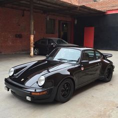 a black porsche parked in front of a brick building