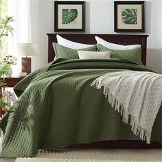 a bed with green bedspread and white pillows