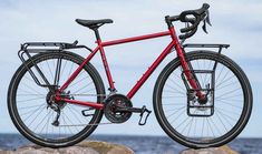 a red bike parked on top of a rock near the ocean