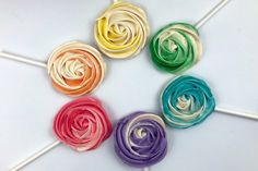 six colorful lollipops are arranged in a circle on a white table top