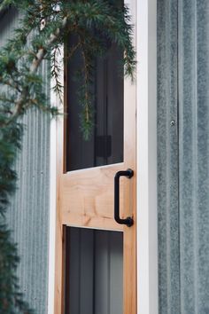 a close up of a wooden door with a handle on it's side and trees in the background