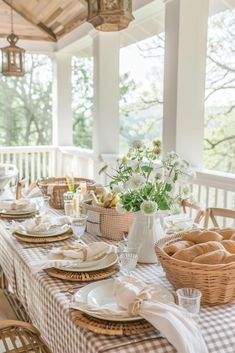 a dining table set with plates and place settings for two people on the front porch