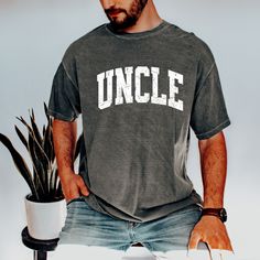 "FREE SHIPPING IN THE US! Comfort Colors, Uncle Shirt, Gift for Uncle, Uncle Gift, New Uncle Gift,  Matching Shirts, Aunt and Uncle Shirts, Announcement Shirt Uncle ♥ The SHIRT  * This is a Comfort Colors 1717 shirt.  * This unisex fit t-shirt is intended to be loose/oversized for women to give a chic and laid back vibe. If you want the tee to be more fitted, we would recommend sizing down.   * If you are looking for an oversized \"T-shirt Dress\" look, we recommend sizing up 1 or 2 sizes  * Detailed sizing information can be found in the size chart in the photos.  * Printed in the USA ♥ CARE  ＊Machine wash cold, inside-out, gentle cycle ＊Wash with mild detergent and similar colors ＊Tumble dry low or hang-dry ＊Do not bleach or fabric softeners ＊Do not iron directly onto the design ＊Do not Relaxed Fit Short Sleeve Shirt With Lettering, Casual Gray Shirt With Letter Print, Casual Slogan Shirt For College, Casual Gray T-shirt With Name Print, Casual Gray Tops With Name Print, Gray Casual Tops With Name Print, Casual Relaxed Fit Shirt With Name Print, Casual Cotton Shirt With Name Print, Casual College Shirt With Name Print