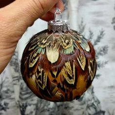 a hand holding a glass ornament with an image of a butterfly on it