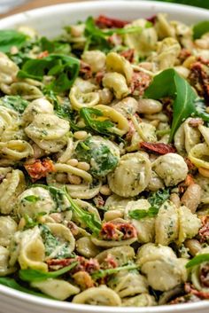 a white bowl filled with pasta and spinach