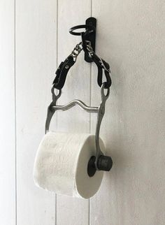 a roll of toilet paper hanging from a metal holder on a white wall with a chain attached to it