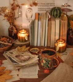 a table topped with books and candles next to fall leaves on top of each other