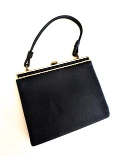 A classic 60s black nylon kiss lock top handle hand bag. Simple yet elegant purse with clean lines and bright gold tone trim. Ships USA, fast free shipping. Measures approx. 6"x8" Nice clean vintage condition no smells or stains  Please see additional pics for more details and measurements  Shipping includes tracking and insurance  thejewelrycabinet.etsy.com www.instagram.com/thejewelrycabinet  www.fb.com/thejewelrycabinet Kiss Lock Purse, Elegant Purse, Small Black Purse, Silver Springs, Black Purse, Bright Gold, Bag Vintage, Black Purses, Black Nylon