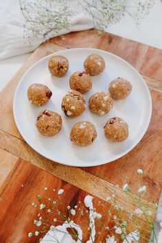 a white plate topped with cookies on top of a wooden cutting board next to flowers