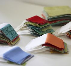 a pile of folded cloths sitting on top of a white table next to each other