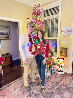 a man and woman standing in front of a christmas tree