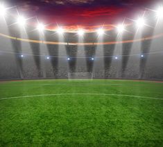 an empty soccer field at night with bright lights and floodlights on the stadium's stands