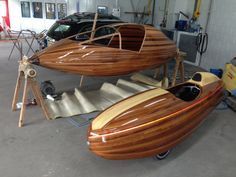 two wooden boats sitting in a garage next to each other