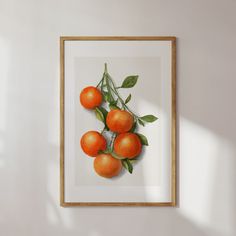 an orange print hangs on the wall in front of a white wall with a wooden frame