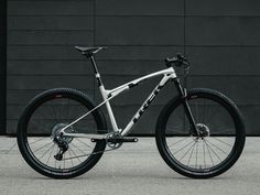 a white mountain bike parked in front of a black building with no wheels on it