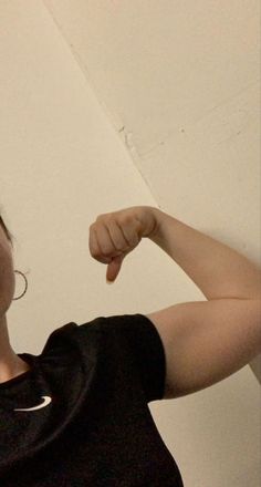 a woman is holding her arm up and posing for the camera while wearing a black t - shirt