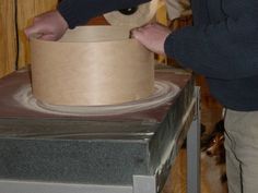 a man is making a vase out of toilet paper on top of a table with a dog in the background