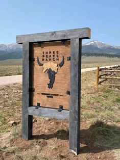 there is a sign that says three forks ranch in front of the mountains and dirt road