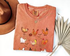 This fun and festive Halloween Chicken Shirt is perfect for anyone who wants to celebrate the holiday in style! The shirt features a design that is sure to turn heads, and it's made from a comfortable and durable material that will last through all the Halloween festivities.  ★ Comfort Colors Shirt: Comfort Colors introduces its garment-dyed t-shirt; a fully customizable tee made 100% with ring-spun cotton. The soft-washed, garment-dyed fabric brings extra coziness to your wardrobe while the rel Fall Novelty T-shirt With Funny Print, Funny Print Novelty T-shirt For Fall, Novelty T-shirt With Funny Print For Fall, Novelty Character Print Tops For Fall, Fun Custom Print Tops For Fall, Halloween Chicken, Chicken Halloween, Ghost Tee, Chicken Shirt