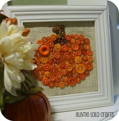 an orange and white flower sitting in front of a framed picture with buttons on it