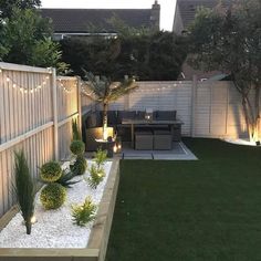 a small backyard with grass and lights on the fence