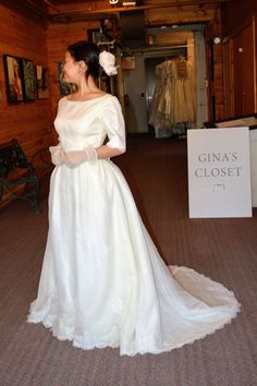 a woman in a white wedding dress standing next to a sign that says gina's closet