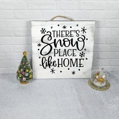 there's snow place we home sign next to a small christmas tree and glass ornament