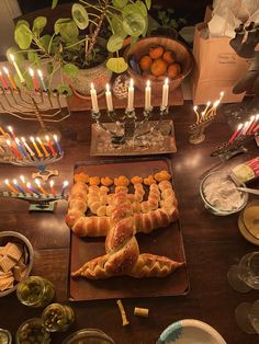 a wooden table topped with lots of food and candles