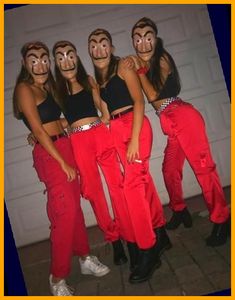 four women with painted faces and red pants are posing for a photo in front of a garage door