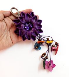 a hand holding a purple flower and some beads