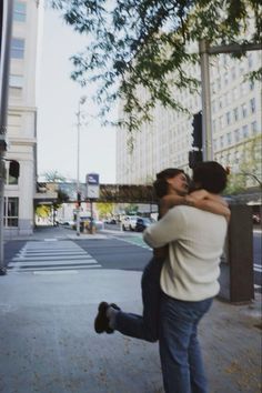 two people hugging each other on the street