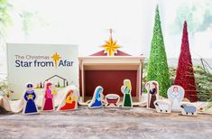 wooden nativity scene displayed on table with christmas tree and star from afar sign in background