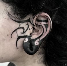 a woman with black and white tattoos on her ear