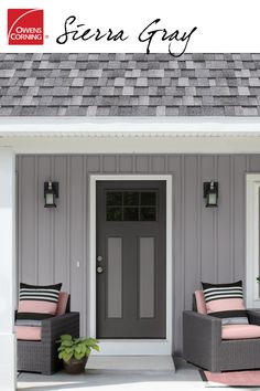 two chairs sitting on the front porch of a gray house with pink cushions and pillows