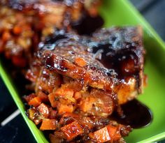 a green plate topped with meat covered in bbq sauce and sweet potato cubes