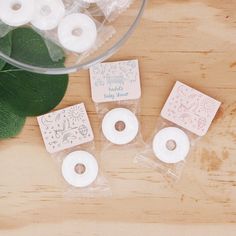 four small donuts sitting on top of a wooden table next to a green leaf