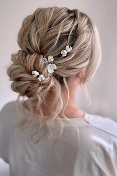 Elegant twisted updo with delicate white floral accessories creates a romantic bridal hairstyle. Light blonde tones add a soft touch to the intricate texture of the hair. Perfect for special occasions.  // Photo Credit: Instagram @staciegoodwinbridalhair Bridal Hair Romantic Updo, Bridal Hair Updo Elegant, Romantic Wedding Hair Updo, Bridal Hair Blonde, White Wedding Guest Dresses, Bridesmaid Hair Up, Bride Hairstyles Updo, Gorgeous Wedding Hairstyles, Shiny Black Hair