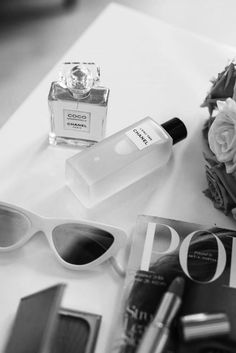 an assortment of perfumes, sunglasses and flowers on a white counter top with the word posh written in black