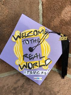 a purple and yellow graduation cap with the words welcome to the real world on it