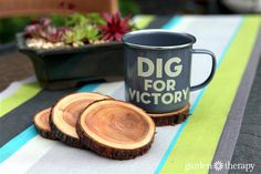 two pieces of wood sitting on top of a table next to a mug and potted plant