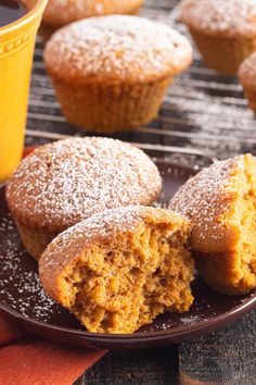 some muffins are on a plate with a cup of coffee in the background